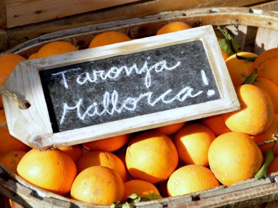 Piles of fresh oranges, tomatoes, and other seasonal produce at a Mallorcan market